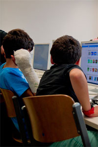Drei Personen sitzen nebeneinander vor Computerbildschirmen.