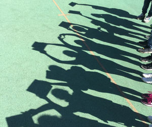 Foto des Schattens einer Personengruppe, die verschiedene Gegenstände hochhält.