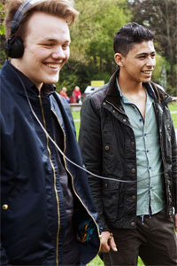 Zwei junge Männer mit Film-Equipment lachen in die Kamera.