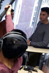 Zwei junge Männer stehen voreinander. Im Vordergrund steht eine weitere Person, welche Kopfhörer trägt und eine Tonangel hält.